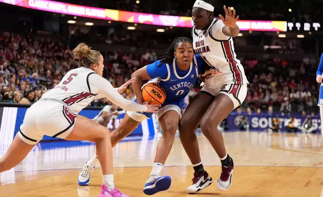 Kentucky guard Jordan Obi drives to the basket between South Carolina guard Tessa Johnson and center Madina Okot during first half of an NCAA college basketball game in the quarterfinals of the Southeastern Conference tournament, Friday, March 6, 2026, in Greenville, S.C. (AP Photo/Chris Carlson)
