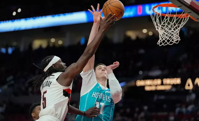 Portland Trail Blazers guard Jrue Holiday (5) shoots as Charlotte Hornets center Ryan Kalkbrenner (11) defends during the first half of an NBA basketball game Tuesday, March 10, 2026, in Portland, Ore. (AP Photo/Jenny Kane)