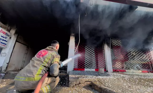 A firefighter extinguishes a burned shop at a building that was hit by an Israeli airstrike in Dahiyeh, a southern suburb of Beirut, Lebanon, Tuesday, March 3, 2026. (AP Photo/Hussein Malla)