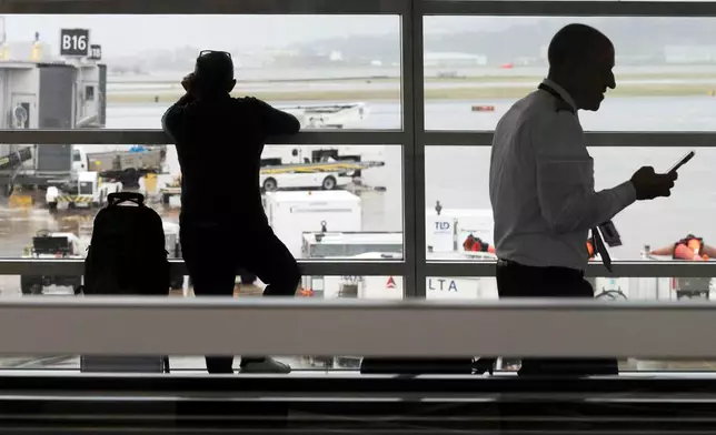 People wait in a departure terminal at Ronald Reagan National Airport, in Arlington, Va., Monday, March 16, 2026. (AP Photo/Cliff Owen)