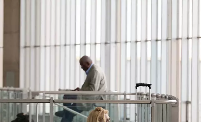 People wait in a departure terminal at Ronald Reagan National Airport, in Arlington, Va., Monday, March 16, 2026. (AP Photo/Cliff Owen)