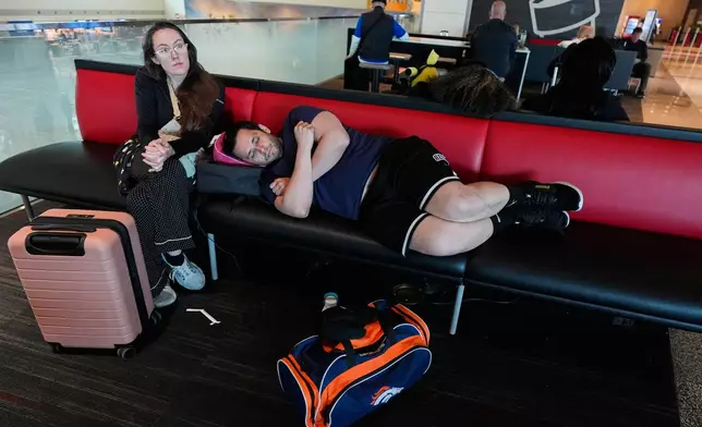 Jamie Sims left, and Carlos Serna, right, try to get some rest as they wait for their cancelled flight to El Paso, texas to be rescheduled at Love Field Airport in Dallas, Monday, March 16, 2026. (AP Photo/Tony Gutierrez)