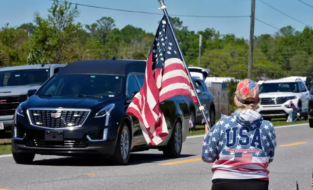 Deb McCutcheon, of Lakeland, salutes as the hearse carrying the remains of U.S. Army Reserve Maj. Cody Khork, a service member killed in the line of duty in the Middle East, after arriving at the Lakeland Linder Airport Wednesday, March 18, 2026, in Lakeland, Fla. (AP Photo/Chris O'Meara)