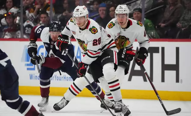Chicago Blackhawks left wing Andre Burakovsky, front, collects the puck as defenseman Louis Crevier, back right, and Colorado Avalanche right wing Valeri Nichushkin pursue in the second period of an NHL hockey game Saturday, Feb. 28, 2026, in Denver. (AP Photo/David Zalubowski)