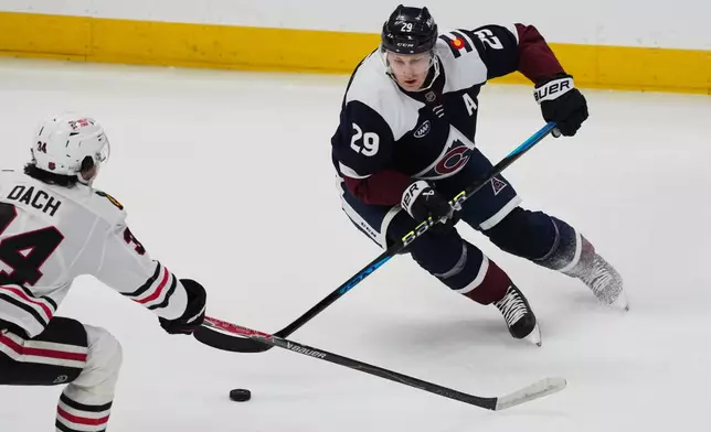 Colorado Avalanche center Nathan MacKinnon, right, looks to pass the puck as Chicago Blackhawks center Colton Dach defends in the first period of an NHL hockey game Saturday, Feb. 28, 2026, in Denver. (AP Photo/David Zalubowski)