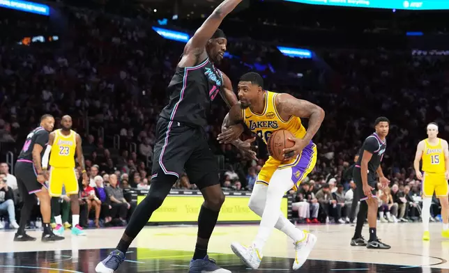 Los Angeles Lakers guard Marcus Smart, right, drives to the basket as Miami Heat center Bam Adebayo, left, defends during the first half of an NBA basketball game, Thursday, March 19, 2026, in Miami. (AP Photo/Lynne Sladky)