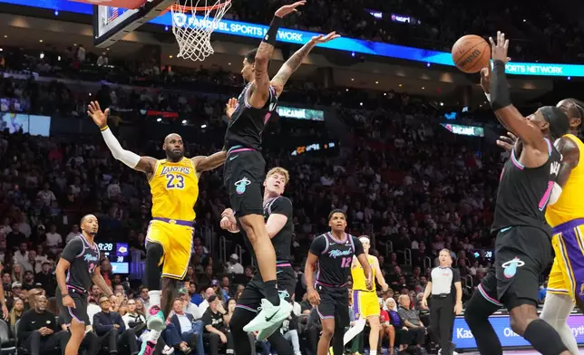 Los Angeles Lakers forward LeBron James (23) attempts to pass as Miami Heat center Bam Adebayo, right, goes for the ball during the first half of an NBA basketball game, Thursday, March 19, 2026, in Miami. (AP Photo/Lynne Sladky)