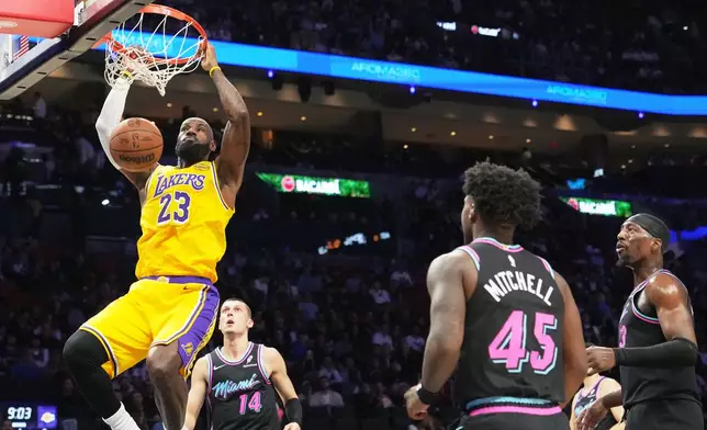 Los Angeles Lakers forward LeBron James (23) dunks over Miami Heat guard Tyler Herro (14) during the first half of an NBA basketball game, Thursday, March 19, 2026, in Miami. (AP Photo/Lynne Sladky)