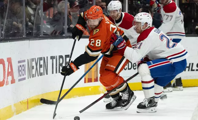 Anaheim Ducks left wing Jeffrey Viel (28) controls the puck away from Montreal Canadiens defenseman Kaiden Guhle (21) during the first period of an NHL hockey game, Friday, March 6, 2026, in Anaheim, Calif. (AP Photo/Kyusung Gong)