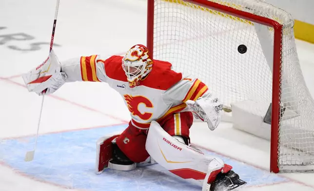 A puck shot by Washington Capitals center Justin Sourdif, not shown, gets past Calgary Flames goaltender Devin Cooley (1) for a goal during the third period of an NHL hockey game, Monday, March 9, 2026, in Washington. (AP Photo/Nick Wass)