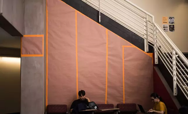 Students sit in front of a covered mural of Cesar Chavez at Santa Ana College in Santa Ana, Calif., Thursday, March 19, 2026. (AP Photo/Jae C. Hong)