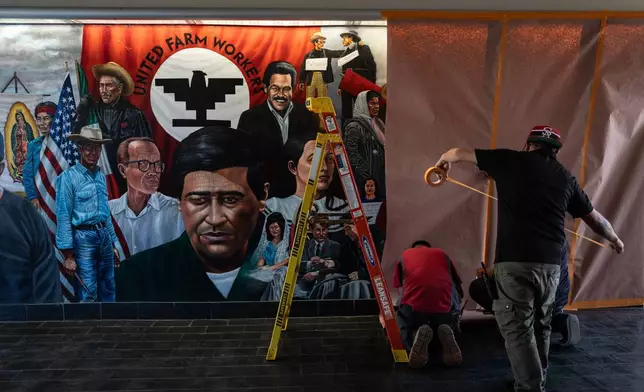 Workers cover a mural by Emigdio Vasquez featuring Cesar Chavez and other figures at Santa Ana College in Santa Ana, Calif., Thursday, March 19, 2026. (AP Photo/Jae C. Hong)