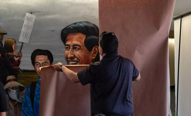 A worker covers a mural by Emigdio Vasquez depicting Cesar Chavez, at Santa Ana College in Santa Ana, Calif., Thursday, March 19, 2026. (AP Photo/Jae C. Hong)