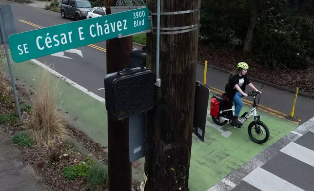 A bicyclist waits to cross SE César E Chávez Boulevard on Wednesday, March 18, 2026, in Portland, Ore. (AP Photo/Jenny Kane)