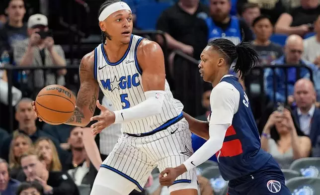 Orlando Magic forward Paolo Banchero (5) looks to pass the ball as Washington Wizards guard Bub Carrington defends during the first half of an NBA basketball game, Tuesday, March 3, 2026, in Orlando, Fla. (AP Photo/John Raoux)
