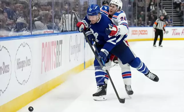Toronto Maple Leafs defenseman Jake McCabe (22) gets checked by New York Rangers forward Tye Kartye (24) during the third period of an NHL hockey game, in Toronto, Wednesday, March 25, 2026. (Nathan Denette/The Canadian Press via AP)