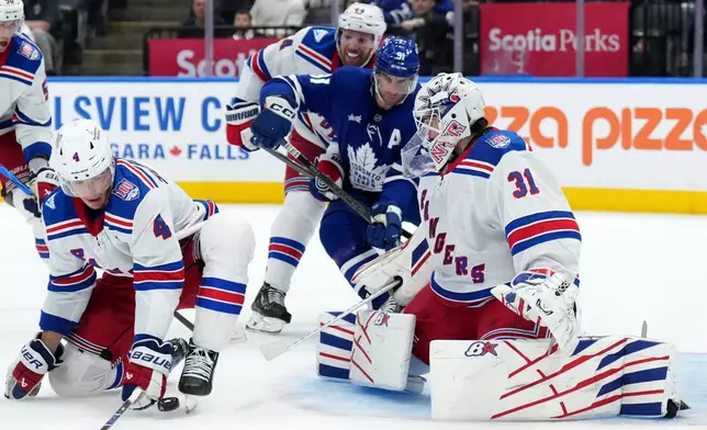 New York Rangers defenceman Braden Schneider (4) blocks a shot on teammate Igor Shesterkin (31) as Toronto Maple Leafs forward John Tavares (91) looks on during the second period of an NHL hockey game in Toronto, Wednesday, March 25, 2026. (Nathan Denette/The Canadian Press via AP)