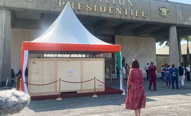 Francoise Remarck, Ivorian minister of Culture, stands in front of the crate containing a looted sacred talking drum, in Abidjan, Ivory Coast, Friday, March 13, 2026. (AP Photo/Marine Jeannin)