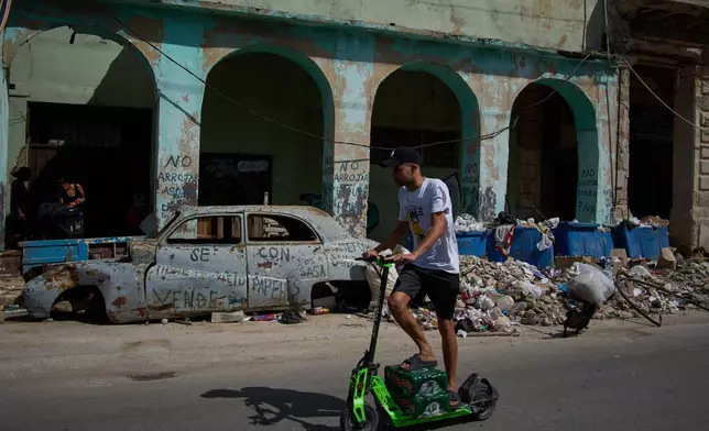 A man rides a scooter past a wrecked car and garbage during a blackout in Havana, Wednesday, March 4, 2026. (AP Photo/Ramon Espinosa)