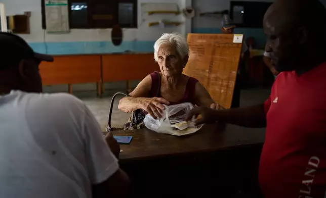 A woman receives a donation from Mexico at a state-run bodega during a blackout in Havana, Wednesday, March 4, 2026. (AP Photo/Ramon Espinosa)