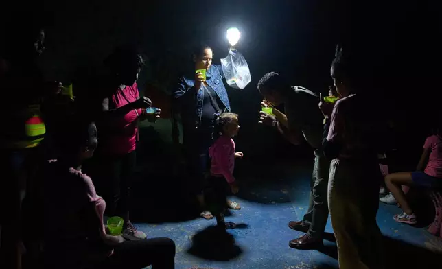 A man gives a girl a spoonful of soup on a street during a blackout in Havana, Wednesday, March 4, 2026. (AP Photo/Ramon Espinosa)