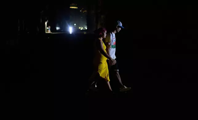 People cross a street during a blackout in Havana, Wednesday, March 4, 2026. (AP Photo/Ramon Espinosa)