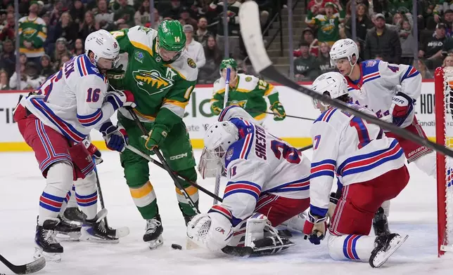 New York Rangers goaltender Igor Shesterkin (31) reaches for the puck while pressured by Minnesota Wild center Joel Eriksson Ek (14) during the third period of an NHL hockey game, Saturday, March 14, 2026, in St. Paul, Minn. (AP Photo/Abbie Parr)