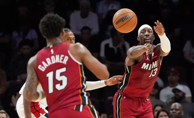 Miami Heat center Bam Adebayo (13) passes to forward Myron Gardner (15) as Washington Wizards center Alex Sarr looks on during the first half of an NBA basketball game, Tuesday, March 10, 2026, in Miami. (AP Photo/Rebecca Blackwell)