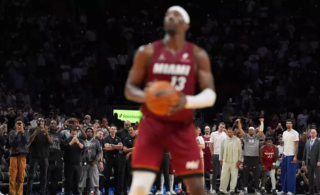 Fans and Miami Heat players on the bench stand to watch as center Bam Adebayo (13) takes a free throw, on his way to scoring 83 points, the second-highest single game total in NBA history, in an NBA basketball game against the Washington Wizards, Tuesday, March 10, 2026, in Miami. (AP Photo/Rebecca Blackwell)