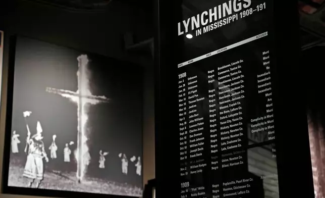 FILE - A monolith listing the names, dates and rationale for the lynching of African-American residents rests in the foreground of a photograph of a burning Ku Klux Klan cross on display in the Mississippi Civil Rights Museum in Jackson, Miss, Nov. 10, 2017. (AP Photo/Rogelio V. Solis, file)