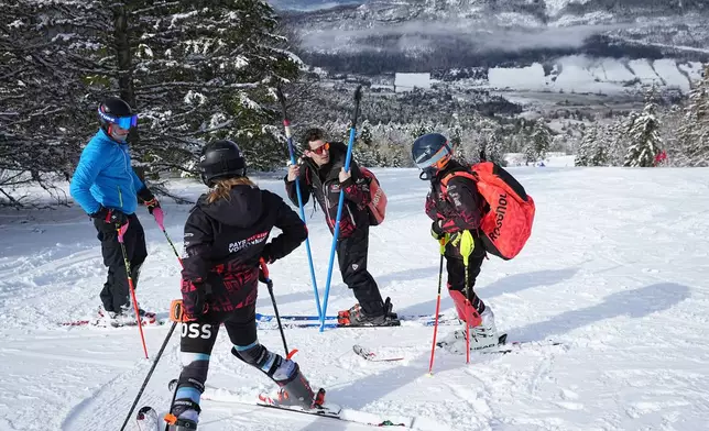 Coach Jeremie Barnier chats with his athletes at the end of a training ski session in Lans-en-Vercors, near Grenoble, France, Friday, Feb. 13, 2026. (AP Photo/Laurent Cipriani)