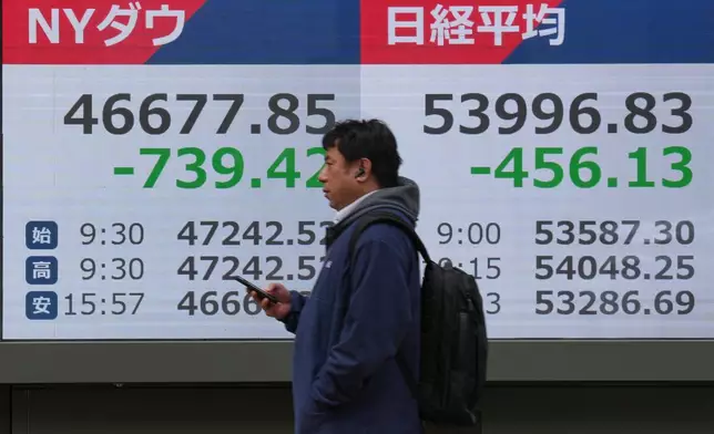 A person walks in front of an electronic stock board showing Japan's Nikkei index at a securities firm Friday, March 13, 2026, in Tokyo. (AP Photo/Eugene Hoshiko)