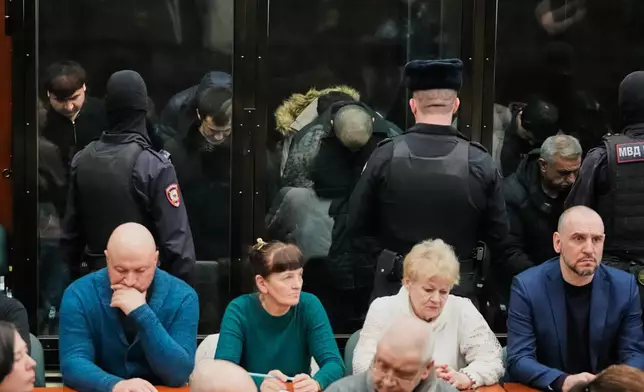 Men tried on the charges of involvement in a terror attack at the Crocus City Hall in March 2024, background, listen to the verdict from behind a glass cage at the Second Western District Military Court in Moscow, Russia, Thursday, March 12, 2026. (AP Photo/Pavel Bednyakov)