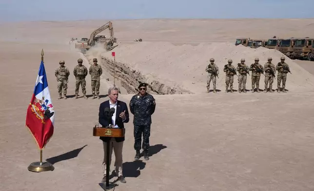 Chilean President Jose Antonio Kast gives a press conference as a machine digs, as part of measures to deter irregular migration, along the northern border at the Chacalluta border crossing, in Arica, Chile, Monday, March 16, 2026. (AP Photo/Esteban Felix)