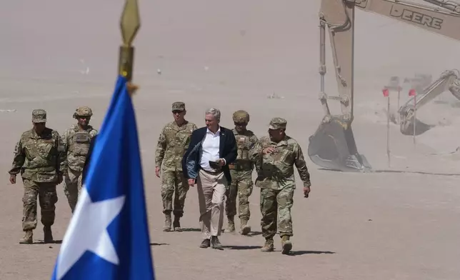 Chilean President Jose Antonio Kast walks past diggers along the northern border at the Chacalluta border crossing in Arica, Chile, Monday, March 16, 2026, as part of measures to deter irregular migration. (AP Photo/Esteban Felix)