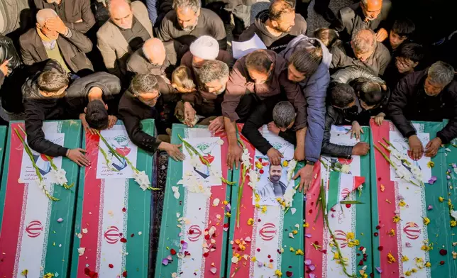 Mourners reach out to coffins during a funeral for people killed during the ongoing U.S.–Israeli military campaign in Qom, Iran, Thursday, March 5, 2026. (Seyyed Mehdi Alavi/ISNA via AP)