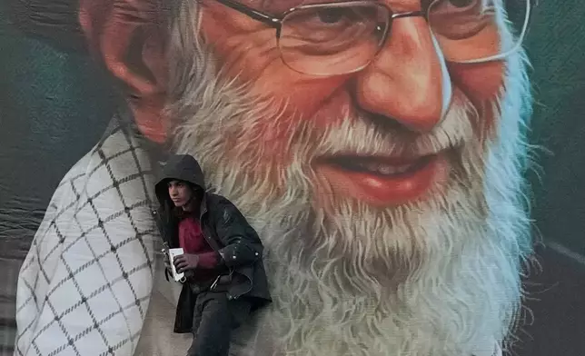 A worker helps install a billboard bearing a portrait of the late Iranian Supreme Leader Ayatollah Ali Khamenei, who was killed during the ongoing joint U.S.-Israeli military campaign, in Tehran, Iran, Monday, March 2, 2026. (AP Photo/Vahid Salemi)
