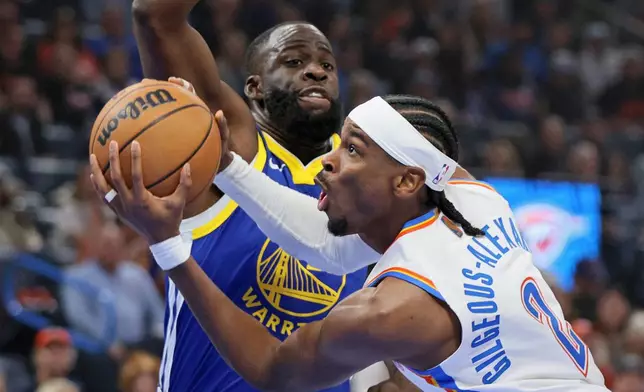 Oklahoma City Thunder guard Shai Gilgeous-Alexander, front, goes to the basket against Golden State Warriors forward Draymond Green, back, during the first half of an NBA basketball game Saturday, March 7, 2026, in Oklahoma City. (AP Photo/Nate Billings)