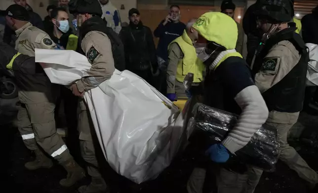 Rescue workers carry a dead body in a plastic bag from a building that was hit by Israeli strike, in Jnah neighborhood, south of Beirut, Lebanon, Monday, March 2, 2026. (AP Photo/Hussein Malla)