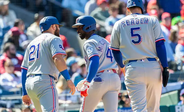 Texas Rangers' Andrew McCutchen, center, celebrates his three run home run with Jake Burger (21) Corey Seager (5) in the fourth inning of a baseball game against the Philadelphia Phillies, Sunday, March 29, 2026, in Philadelphia. (AP Photo/Laurence Kesterson)