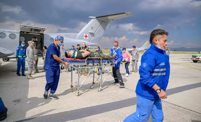 In this photo distributed by Colombia's Armed Forces press office, people who were injured on a military cargo plane that crashed shortly after takeoff in Puerto Leguizamo, arrives at a military base for treatment in Bogota, Colombia, Monday, March 23, 2026. (Colombia's Armed Forces press office via AP)