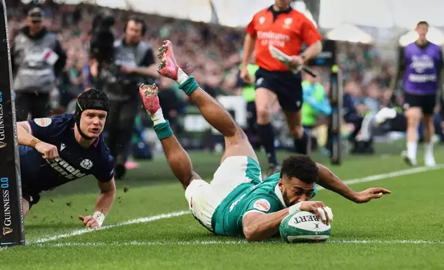 Ireland's Robert Baloucoune, right, scores a try as Scotland's Darcy Graham watches on during the Six Nations rugby union match between Ireland and Scotland, in Dublin, Saturday, March 14, 2026. (AP Photo/Peter Morrison)