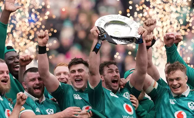 Ireland's Caelan Doris, center, lifts the Triple Crown trophy with teammates after the Six Nations rugby union match between Ireland and Scotland, in Dublin, Saturday, March 14, 2026. (Brian Lawless/PA via AP)