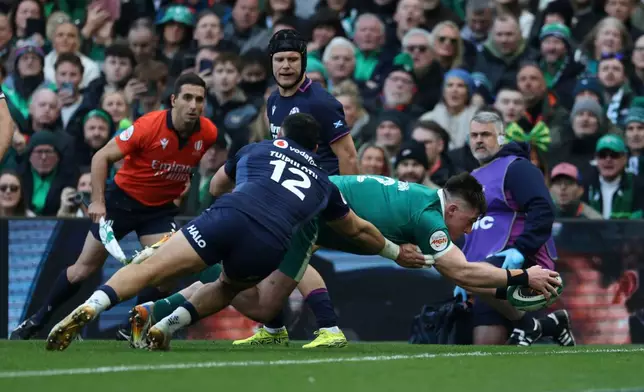Ireland's Dan Sheehan, right, dives over the line to score a try as Scotland's captain Sione Tuipulotu tries to tackle him during the Six Nations rugby union match between Ireland and Scotland, in Dublin, Saturday, March 14, 2026. (AP Photo/Peter Morrison)