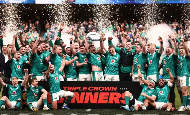 Ireland's team celebrates after winning the "triple crown" trophy following the Six Nations rugby union match against Scotland, in Dublin, Saturday, March 14, 2026. (AP Photo/Peter Morrison)