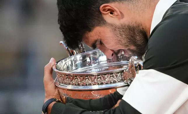 FILE - Spain's Carlos Alcaraz caresses with the trophy after defeating Italy's Jannik Sinner in the final of the French Open tennis tournament, Sunday, June 8, 2025, in Paris. (AP Photo/Lindsey Wasson, File)