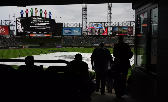 A tarp covers the infield as fans wait during a rain delay before a baseball game between the Los Angeles Angels and the Chicago White Sox in Chicago, Monday, April 27, 2026. (AP Photo/Nam Y. Huh)
