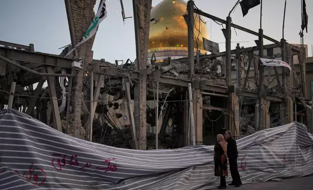 Pedestrians look at a destroyed building within the Grand Hosseiniyeh, with the mosque visible in the background, which officials at the site say was hit by U.S.-Israeli airstrikes Tuesday, in Zanjan, Iran, Saturday, April 4, 2026. (AP Photo/Francisco Seco)