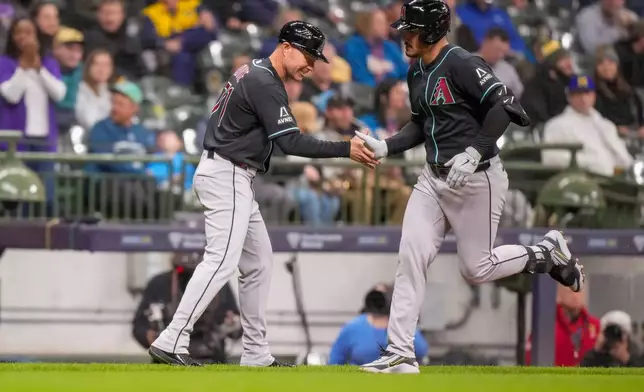 Arizona Diamondbacks' Nolan Arenado rounds the bases on a two-run homer with a shake from third base coach J.R. House during the fourth inning of a baseball game against the Milwaukee Brewers Wednesday, April 29, 2026, in Milwaukee. (AP Photo/Andy Manis)