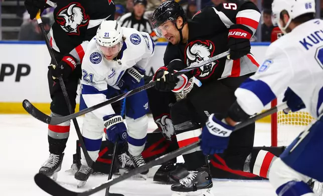 Buffalo Sabres defenseman Luke Schenn (5) clears the puck in front of Tampa Bay Lightning center Brayden Point (21) during the second period of an NHL hockey game Monday, April 6, 2026, in Buffalo, N.Y. (AP Photo/Jeffrey T. Barnes)
